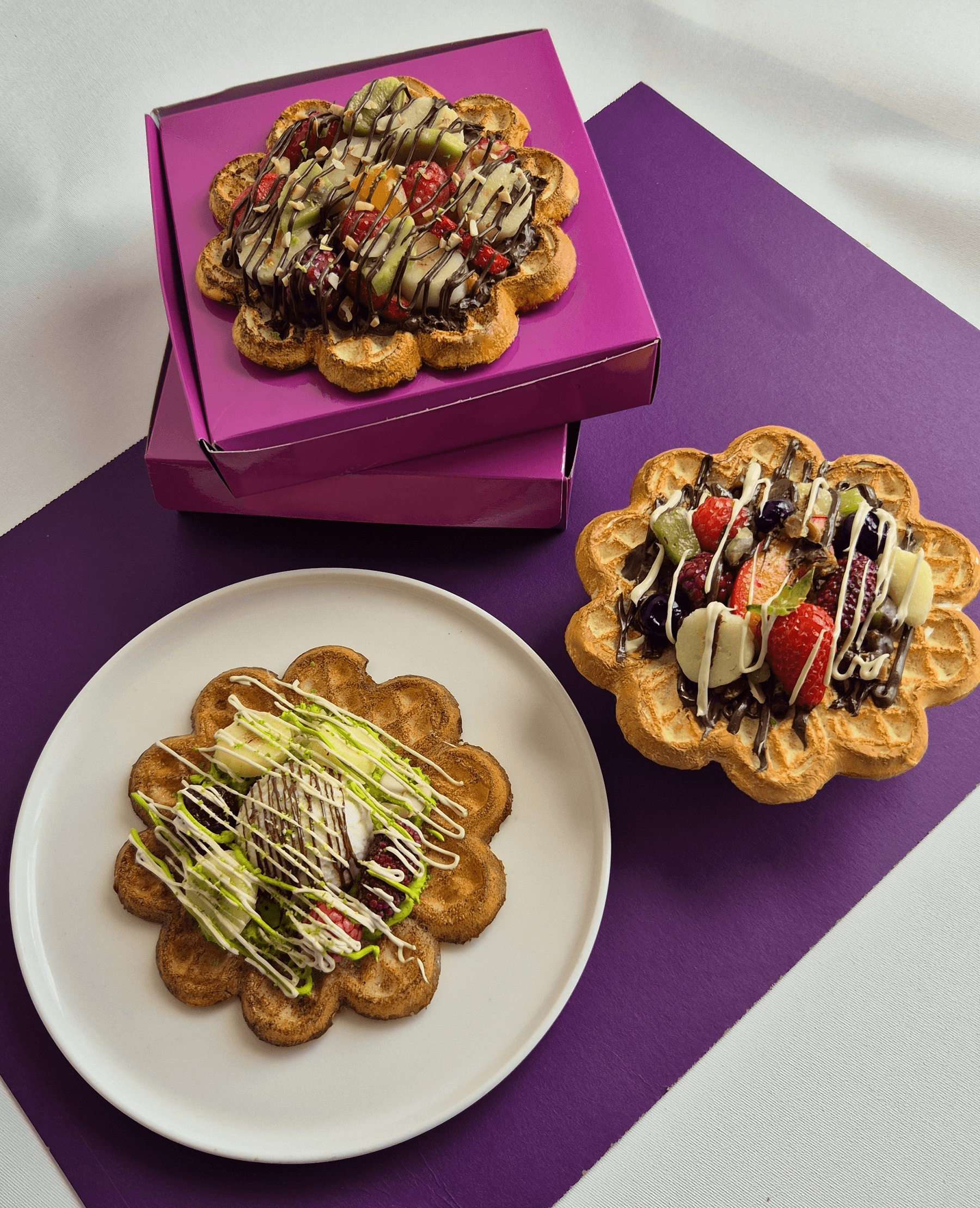Beyaz çikolata soslu, kivili ve dondurmalı muzlu üç el yapımı waffle replikasının sunumu