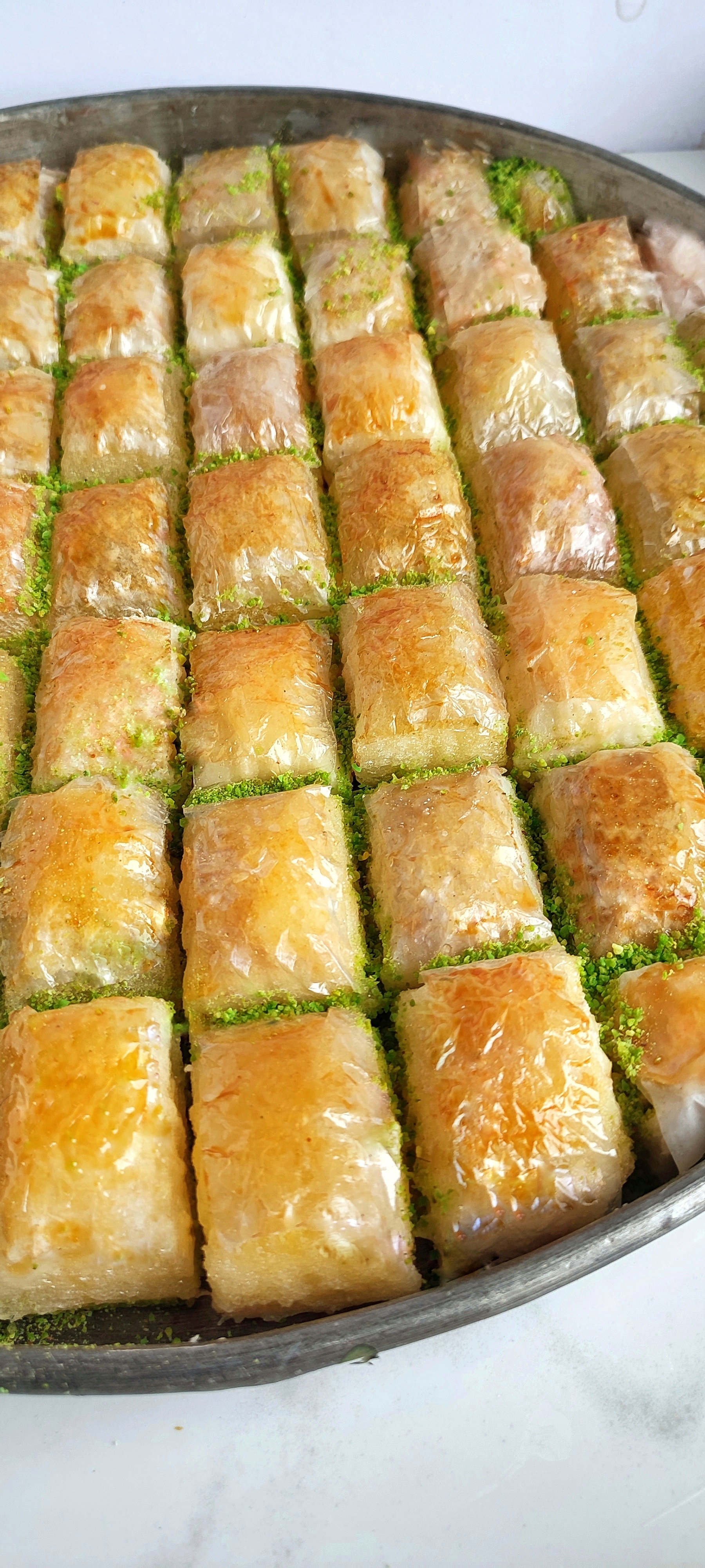 45 cm’lik bakır tepside sıralanan el yapımı Gaziantep fıstıklı baklava replikaları